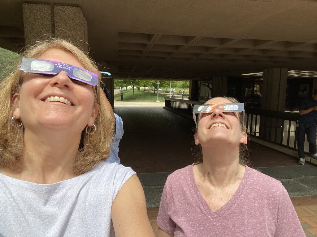 Two women looking up while wearing eclipse viewing glasses